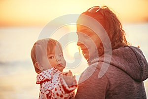 Beautiful sunset in winter. Camping. Parent and child are sitting on the beach by the ocean. Tourism. Mom and daughter admire the