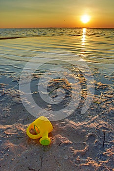 Beautiful sunset with yellow pail left behind on beach