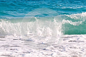 Beautiful surf waves near the sandy beach on a clear summer da