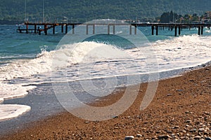 Beautiful surf waves near the sandy beach on a clear summer da