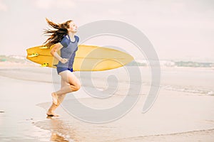 Beautiful surfer girl on the beach at sunset