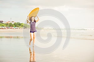 Beautiful surfer girl on the beach at sunset