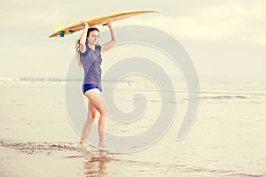 Beautiful surfer girl on the beach at sunset