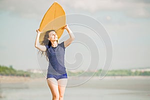 Beautiful surfer girl on the beach at sunset