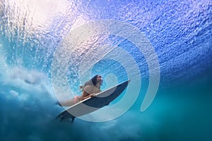 Beautiful surfer girl diving under water with surf board