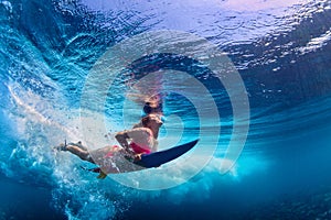 Beautiful surfer girl diving under water with surf board