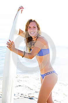 Beautiful surfer teen girl with surfboard on beach