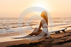 Beautiful surfer woman on the beach at sunset