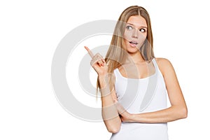 Beautiful surprised woman in excitement pointing to the side. Isolated over white