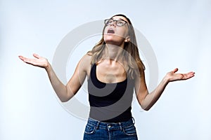 Beautiful surprised young woman with eyeglasses looking to the roof over white background.