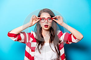 Beautiful surprised young woman in glasses standing in front of