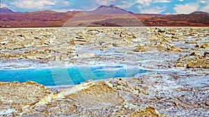 Beautiful surreal desert pan landscape, blue natural water pool, white dry salt crust flat, red mountains volcano Licancabur