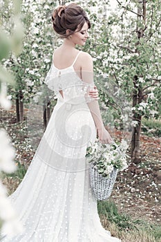 Beautiful sweet gentle happy girl in a beige boudoir dress with flowers in a basket holding , photo processing in the style of mod