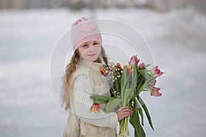 Beautiful sweet girl with a bouquet of tulips in the park in spring