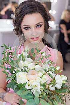 Beautiful sweet girl bridesmaid preparing for the wedding of a friend in the pink evening dress with evening hairstyle and bright