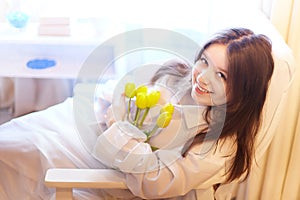 Beautiful sweet girl in nightgown in early morning with bouquet of delicate yellow tulips. Gift on International