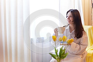 Beautiful sweet girl in nightgown in early morning with bouquet of delicate yellow tulips. Gift on International