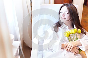 Beautiful sweet girl in nightgown in early morning with bouquet of delicate yellow tulips. Gift on International