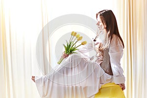 Beautiful sweet girl in nightgown in early morning with bouquet of delicate yellow tulips. Gift on International