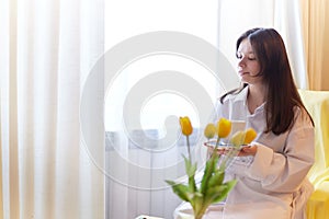 Beautiful sweet girl in nightgown in early morning with bouquet of delicate yellow tulips. Gift on International