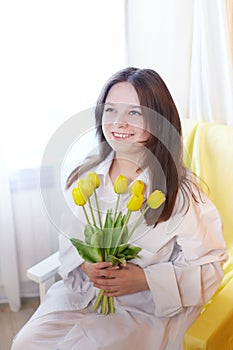 Beautiful sweet girl in nightgown in early morning with bouquet of delicate yellow tulips. Gift on International