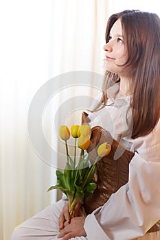 Beautiful sweet girl in nightgown in early morning with bouquet of delicate yellow tulips. Gift on International