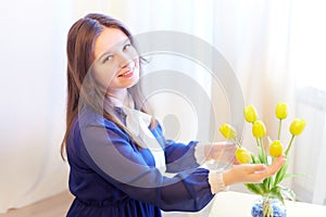 Beautiful sweet manager girl in romantic business dress with fresh flowers in office. A young businesswoman on