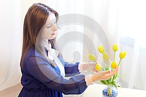 Beautiful sweet manager girl in romantic business dress with fresh flowers in office. A young businesswoman on