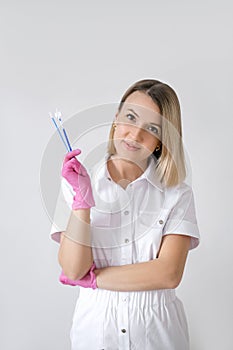 A beautiful, sweet woman gynecologist holds brushes for a cytological smear in her hand.