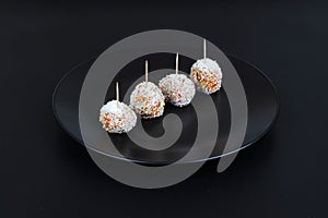 Beautiful sweets with coconut on a black plate on a black background close-up