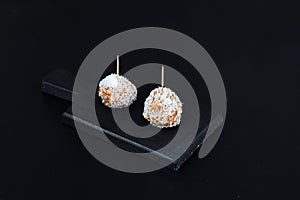 Beautiful sweets with coconut on a black plate on a black background close-up