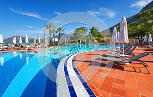 Beautiful swimming pool with sun beds and umbrellas at sunrise