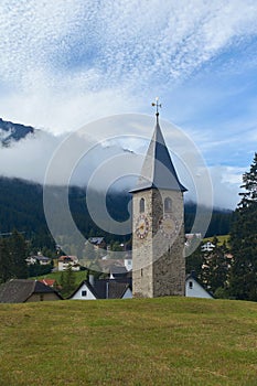 Beautiful swiss alpine countryside with a medieval bell tower with a clock and Rothorn mountain on background in