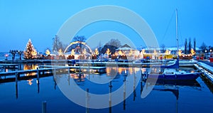 Beautiful swiss christmas market in switzerland on the lake shore with snow covered ships at the blue hour