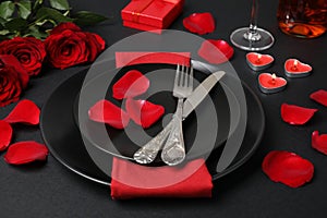 Beautiful table setting with burning candles and bouquet on black table for romantic dinner