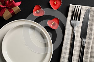 Beautiful table setting with burning candles and decorative hearts on black table for romantic dinner, flat lay