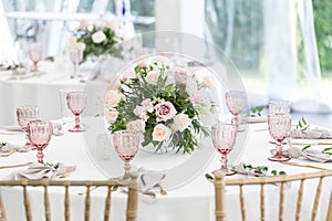 Beautiful table setting with crockery and flowers for a party, wedding reception or other festive event. Glassware and