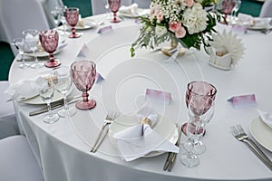 Beautiful table setting with crockery and flowers for a party, wedding reception or other festive event. Glassware and cutlery for