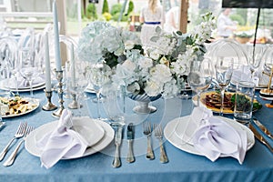 Beautiful table setting for an event on a terrace. Empty plates with napkins