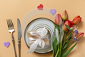 Beautiful table setting with gift box, decorative hearts and tulips flowers