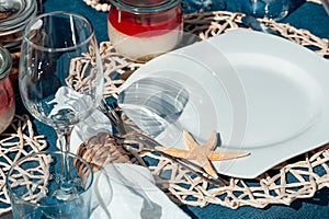 Beautiful table setting with plate, white napkin, braided decorative ring and starfish.