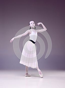 Beautiful talented young woman, professional ballerina, in image of porcelain statue dancing over studio background.