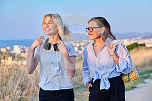 Beautiful talking mom and her teenage daughter outdoors