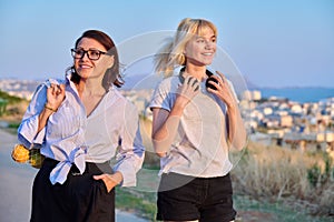 Beautiful talking mom and her teenage daughter outdoors