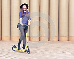 Beautiful tall brunette girl posing on yellow scooter