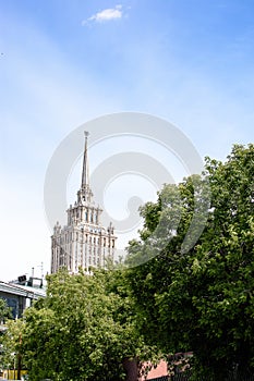 A beautiful tall building, a Stalin skyscraper on the background of a part of the building of the ukraine hotel against the blue s