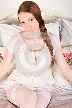 Attractive, innocent girl in a pretty, white negligee, on her bed