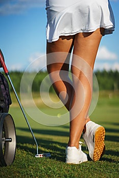Beautiful tanned legs of a golfer girl on the golf course.