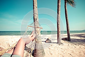 Beautiful Tanned legs of women. relax on hammock at sandy tropical beach