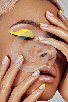 Beautiful tanned skin woman. Sunburnt girl face with natural bronzed make-up, yellow manicure. Sexy summer style makeup photo